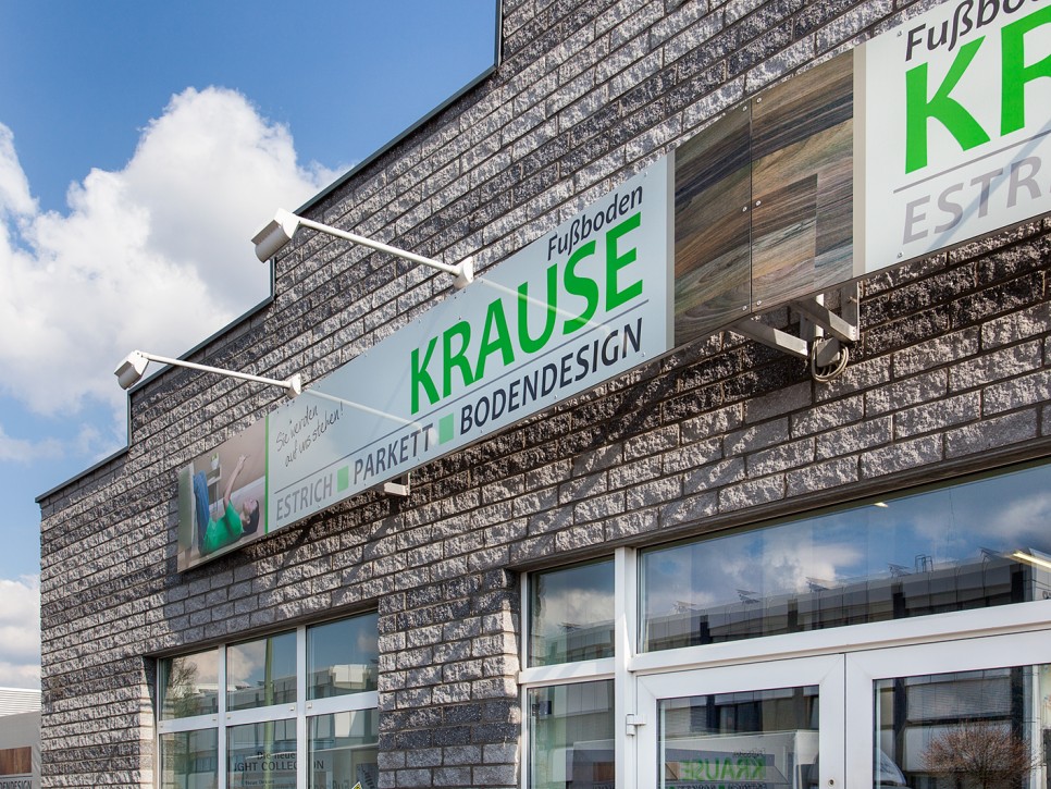 Außenansicht des Firmengebäudes von Fußboden-Krause mit Firmenschild Gebäudefront von Fußboden-Krause mit großem Logo und Beschilderung für Estrich, Parkett und Bodendesign